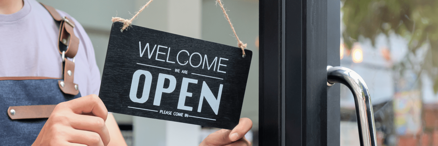 Woman business owner turning 'Business Open' sign on door