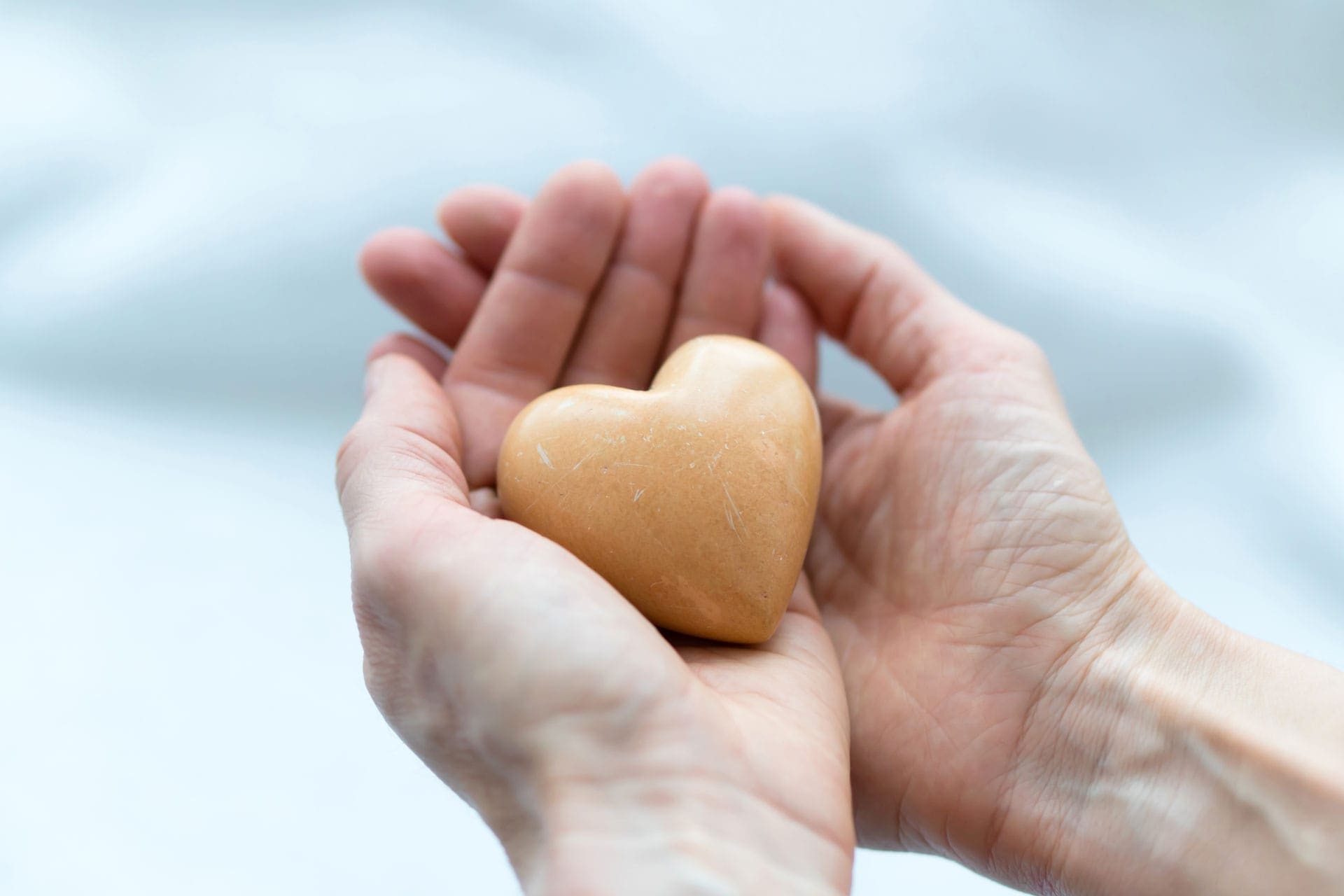 hands holding heart-shaped stone